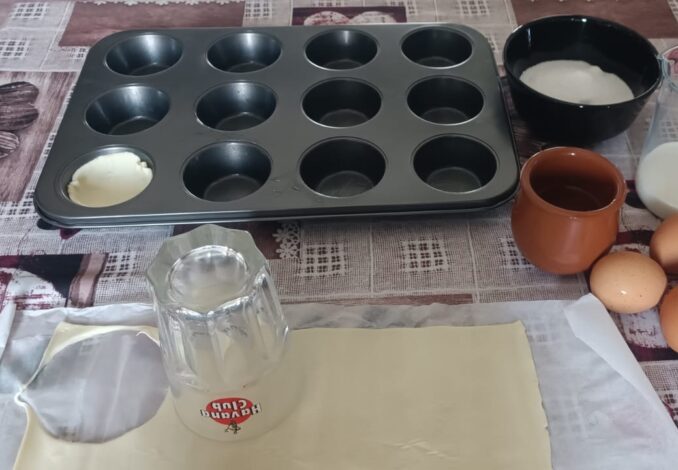 A close-up high-angle shot of freshly baked Pastel de Nata tarts on a rustic wooden table, featuring golden puff pastry crusts and caramelized creamy custard centers, dusted with cinnamon.